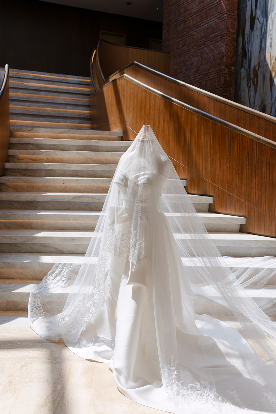 The bride's silk gown and cathedral lace veil arranged on the St. Regis Cap Cana grand staircase